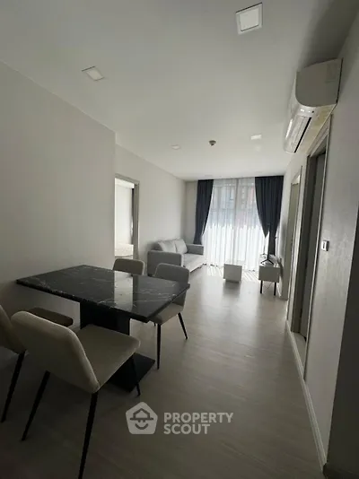 Modern apartment interior with sleek dining area and cozy living room, featuring natural light and contemporary design.
