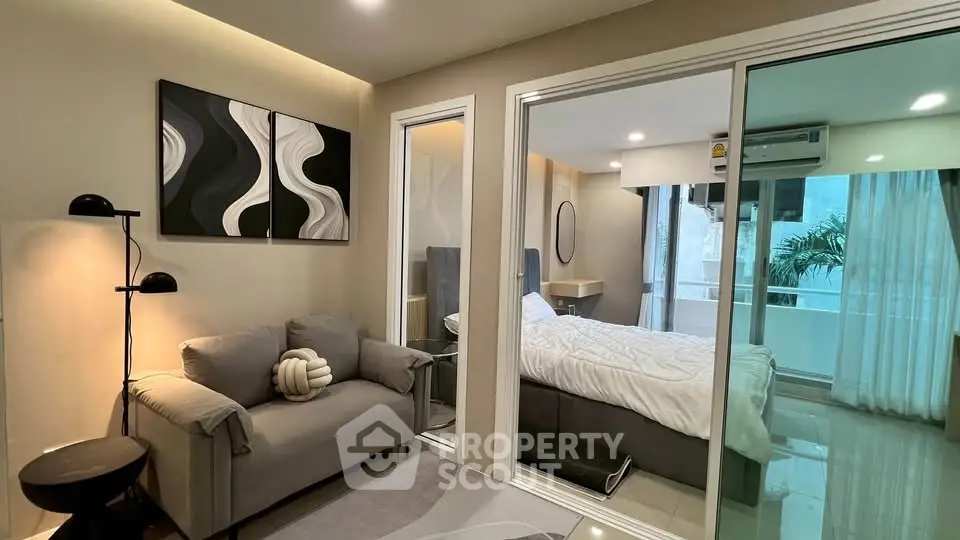 Modern apartment with cozy living room and stylish bedroom separated by glass doors.