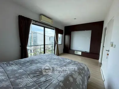 Spacious bedroom with modern decor and large window offering natural light.