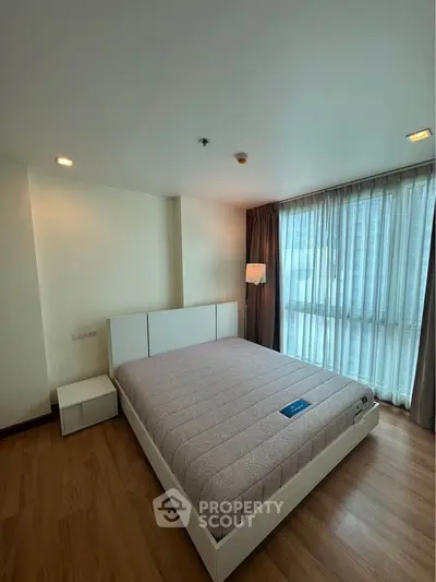 Spacious bedroom with large windows and modern furnishings in a high-rise apartment.