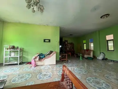 Spacious living room with green walls and patterned tile flooring, featuring a cozy sofa and chandelier.