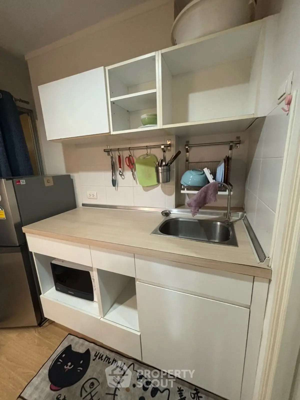 Modern compact kitchen with white cabinets and stainless steel sink, featuring a cozy and efficient design.