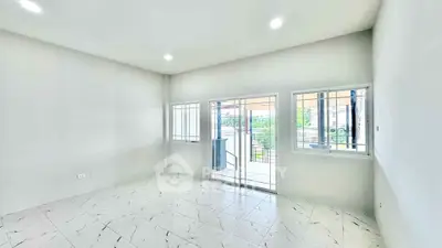 Bright and spacious living room with large windows and modern tile flooring.