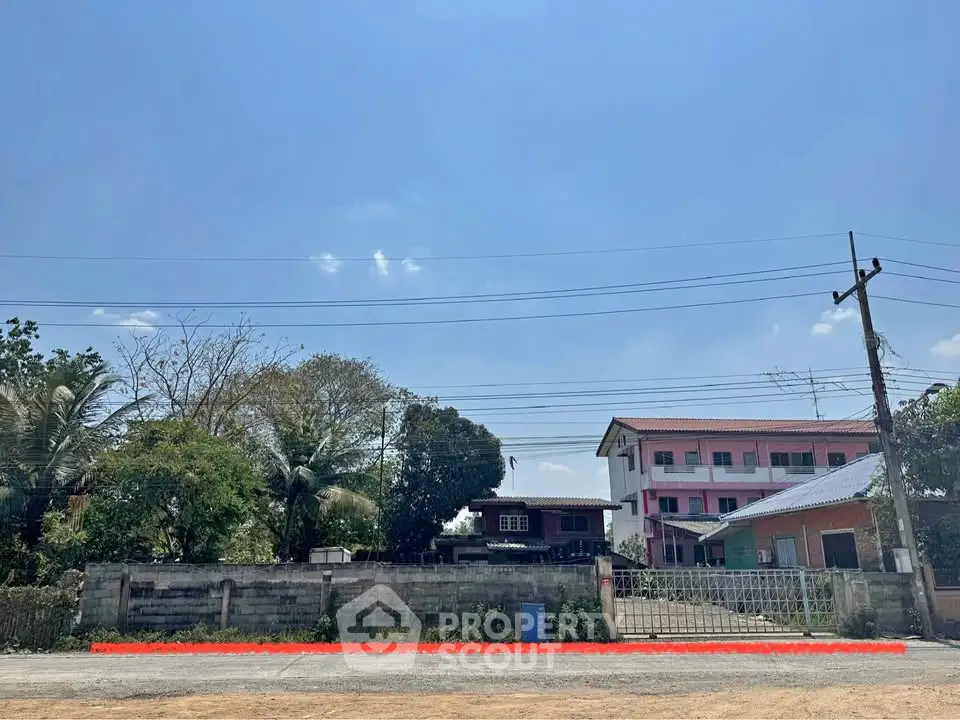 Spacious residential plot with potential for development, featuring clear blue skies and surrounding greenery.