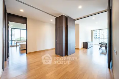 Spacious modern apartment with wooden flooring and large windows offering natural light.