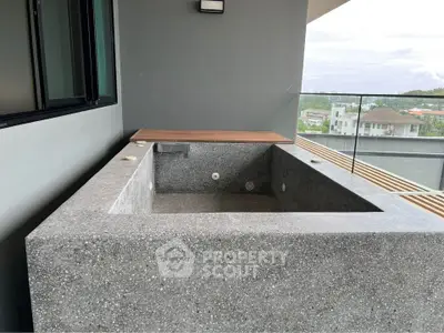 Modern balcony with concrete bathtub and glass railing offering scenic views.