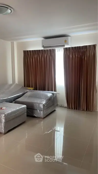 Modern living room with sleek tiled flooring and elegant curtains, featuring a comfortable sofa set.