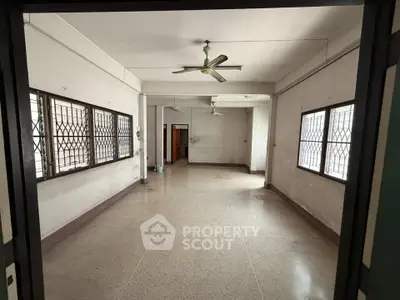 Spacious empty room with large windows and ceiling fans, ideal for customization in a residential property.