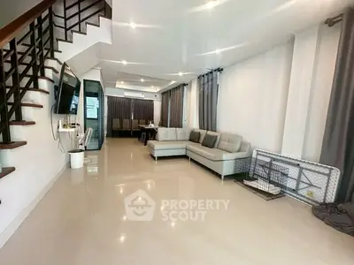 Spacious modern living room with elegant staircase and cozy seating area.