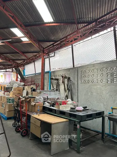Industrial warehouse space with metal roof and concrete walls, ideal for storage or workshop use.