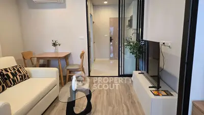 Modern living room with stylish decor and open layout, featuring a cozy seating area and sleek glass table.