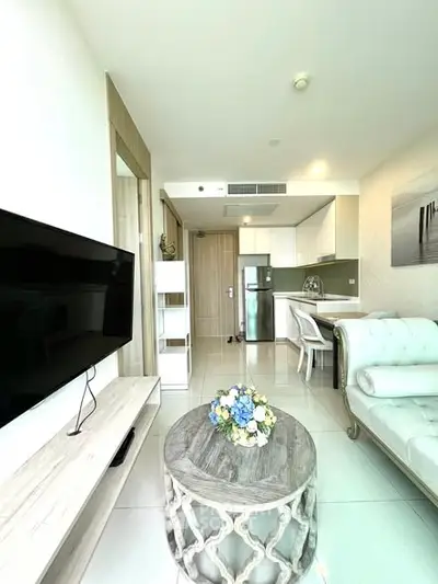 Modern living room with open kitchen, featuring sleek furniture and bright decor.