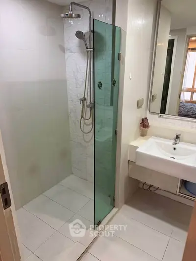 Modern bathroom with glass shower and sleek sink in a contemporary apartment.
