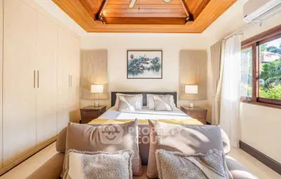 Luxurious bedroom with wooden ceiling and large window offering natural light and garden view.