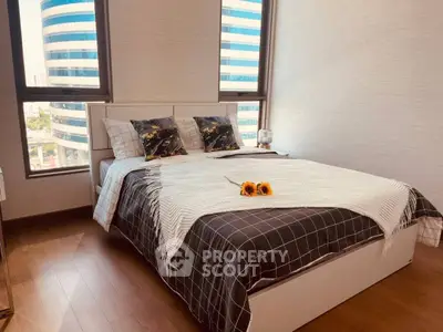 Modern bedroom with stylish decor and large windows offering city views.