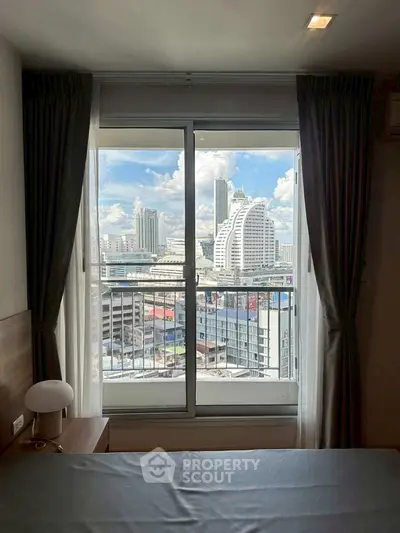 Stunning city view from a modern bedroom with large window and elegant curtains.