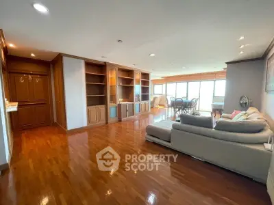 Spacious living room with wooden flooring and built-in shelves, featuring a cozy sofa and dining area.
