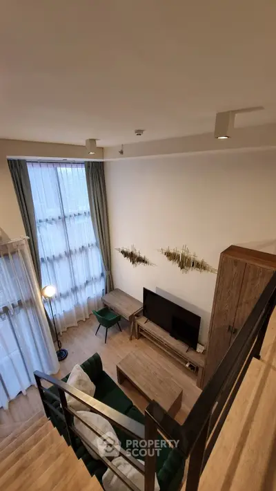 Modern living room with high ceiling and stylish decor, featuring a cozy seating area and large windows for natural light.