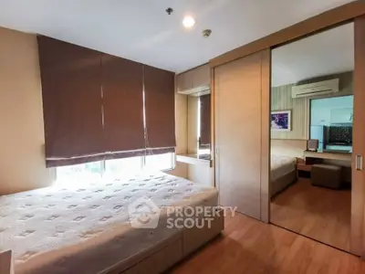 Spacious bedroom with large window and mirrored closet in modern apartment.