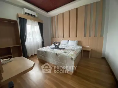 Modern bedroom with stylish wood paneling and cozy decor, featuring a comfortable bed and natural light from large window.