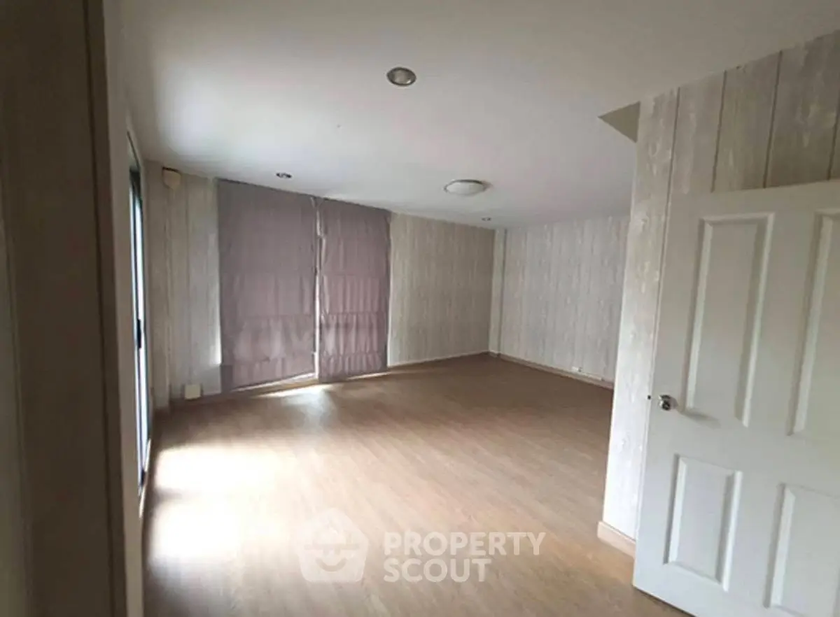 Spacious empty room with wooden flooring and large windows, ideal for customization.