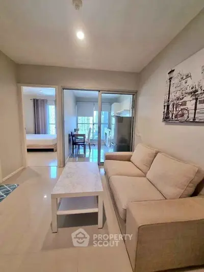 Modern living room with beige sofa and marble coffee table, open to dining area and kitchen.