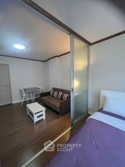 Modern studio apartment with sliding glass partition and cozy furnishings