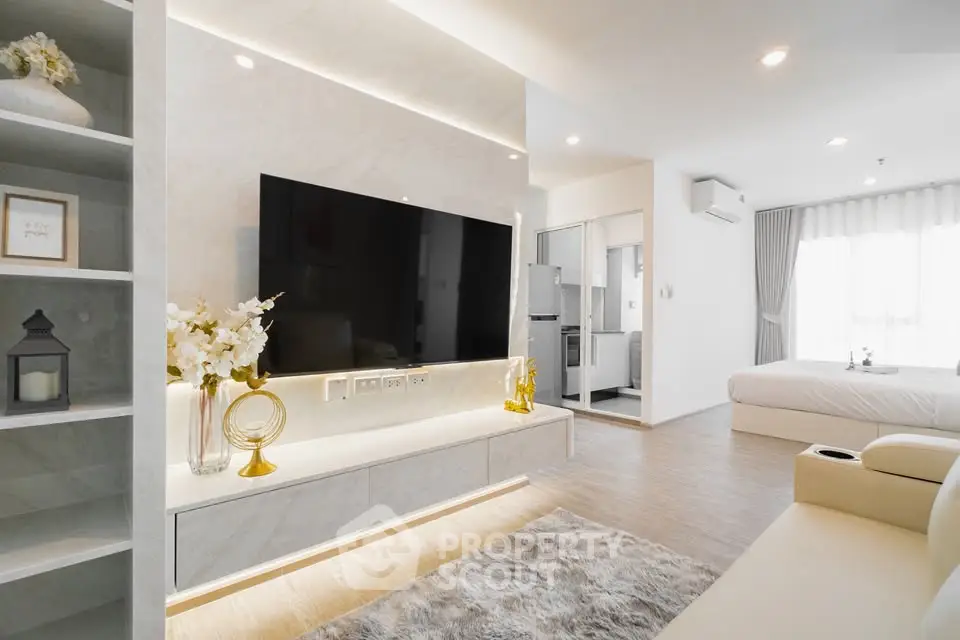 Modern open-plan living room with sleek TV setup and cozy bedroom view