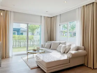 Bright and airy living room with large windows and elegant white sofa, offering a serene garden view.