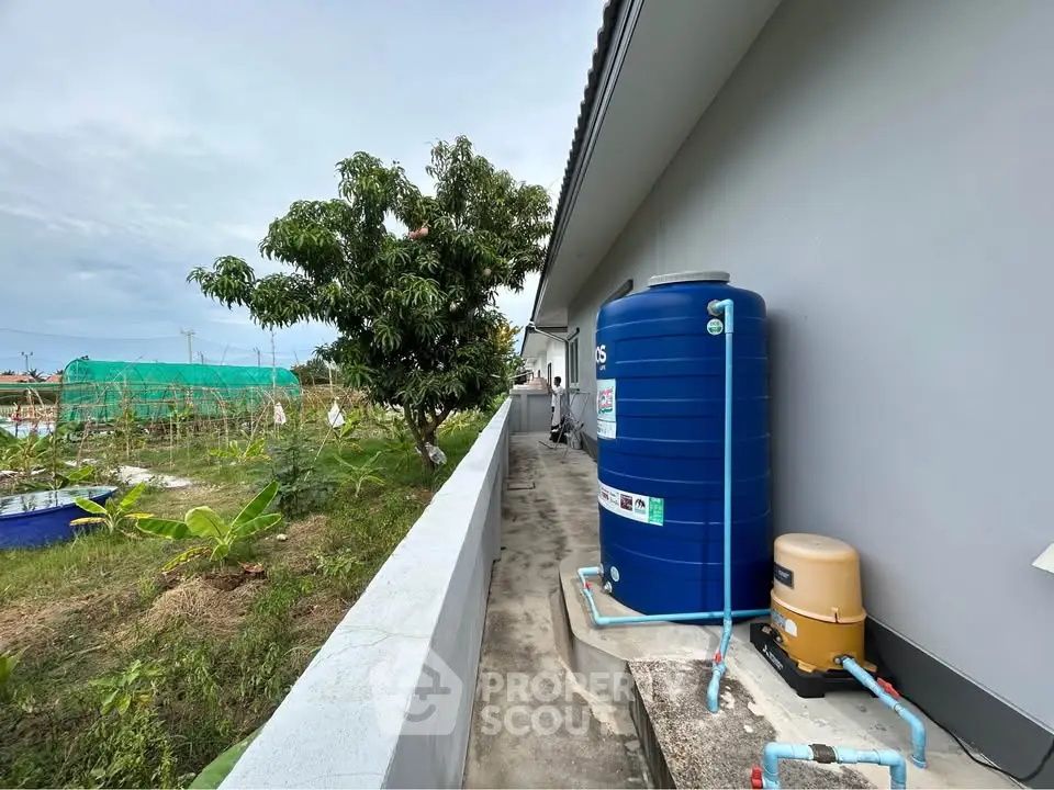 Spacious garden area with water tank and lush greenery, perfect for sustainable living.
