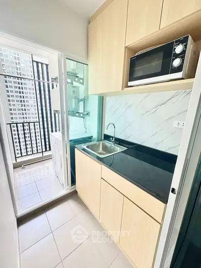 Modern compact kitchen with balcony view in high-rise apartment