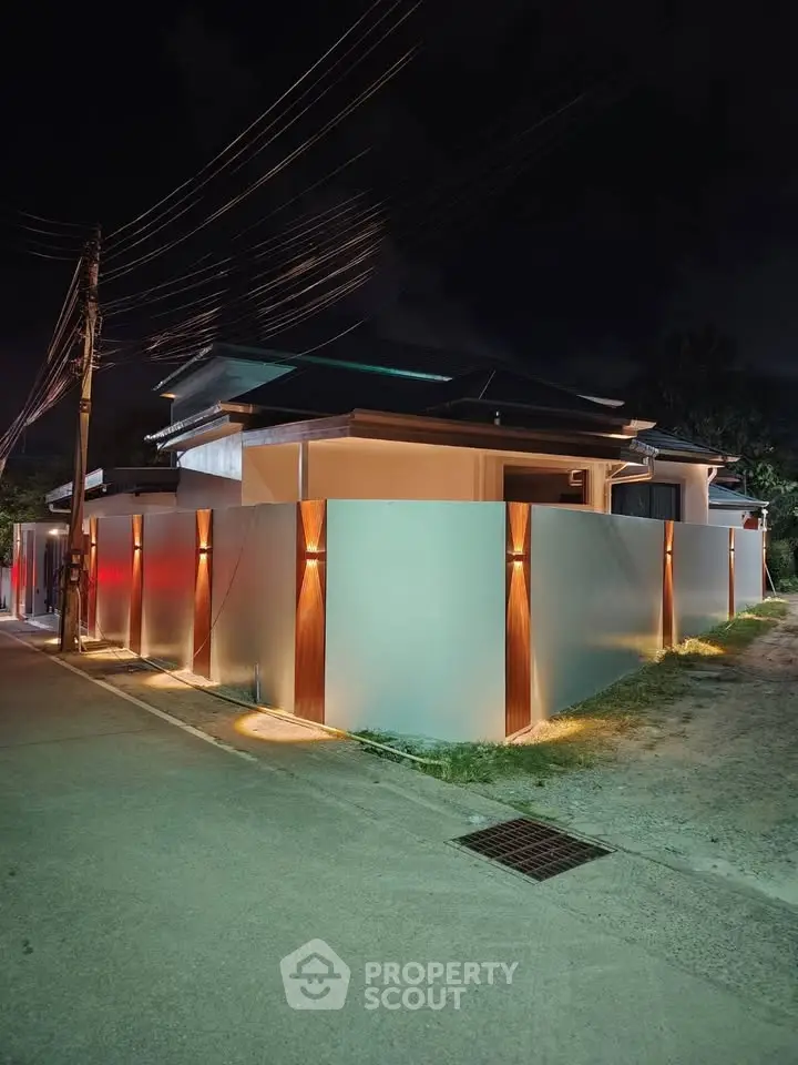 Modern house exterior with sleek design and ambient lighting at night, showcasing privacy and elegance.