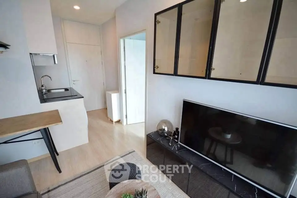 Modern living room with sleek TV unit and compact kitchen area, perfect for urban living.