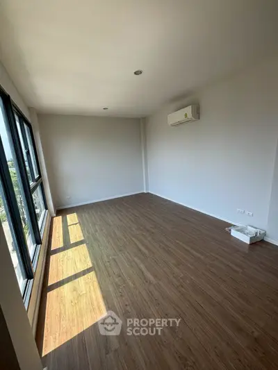 Spacious empty room with large windows and wooden flooring, perfect for customization.
