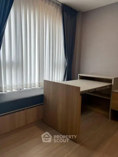 Modern study room with sleek wooden furniture and large window with curtains.