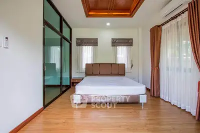 Spacious bedroom with wooden flooring and large windows in modern home