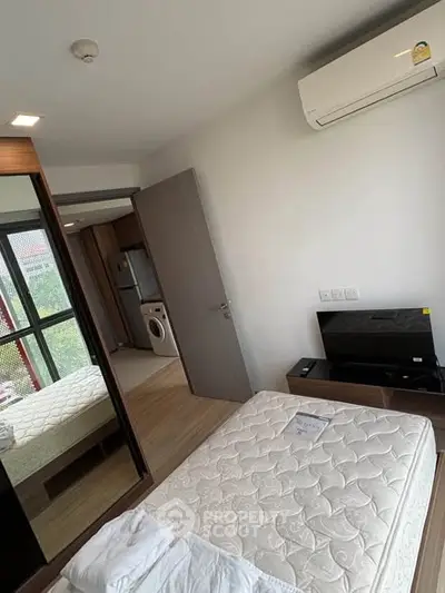 Modern bedroom with air conditioning and mirrored wardrobe, featuring a washing machine in the hallway.