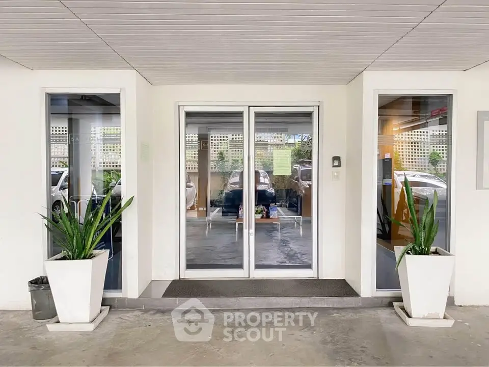 Modern building entrance with glass doors and potted plants, offering a welcoming and stylish entryway.