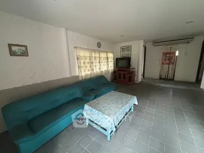 Spacious living room with teal sofa and tiled floor, perfect for family gatherings.