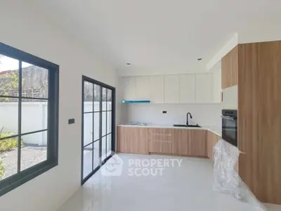 Modern kitchen with sleek cabinetry and large windows in a bright, open space.
