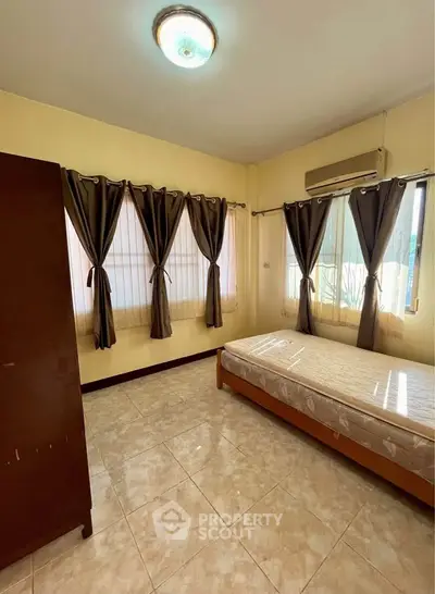 Cozy bedroom with natural light and tiled flooring, featuring a single bed and wardrobe.