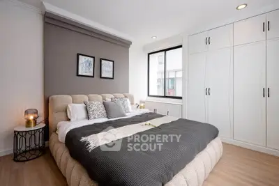 Elegant bedroom with cozy bed, stylish decor, and ample natural light in modern apartment.
