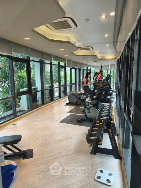 Modern gym with large windows and fitness equipment in a residential building.