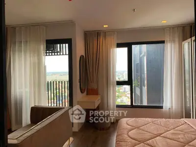 Modern bedroom with large windows and city view, featuring elegant curtains and stylish furniture.