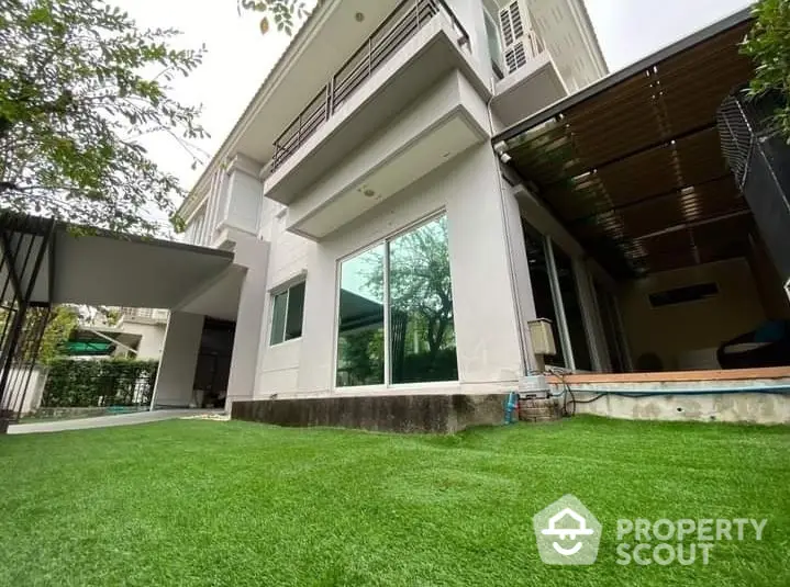 Elegant two-story home with a lush green lawn and spacious outdoor area, featuring large windows and a modern design.