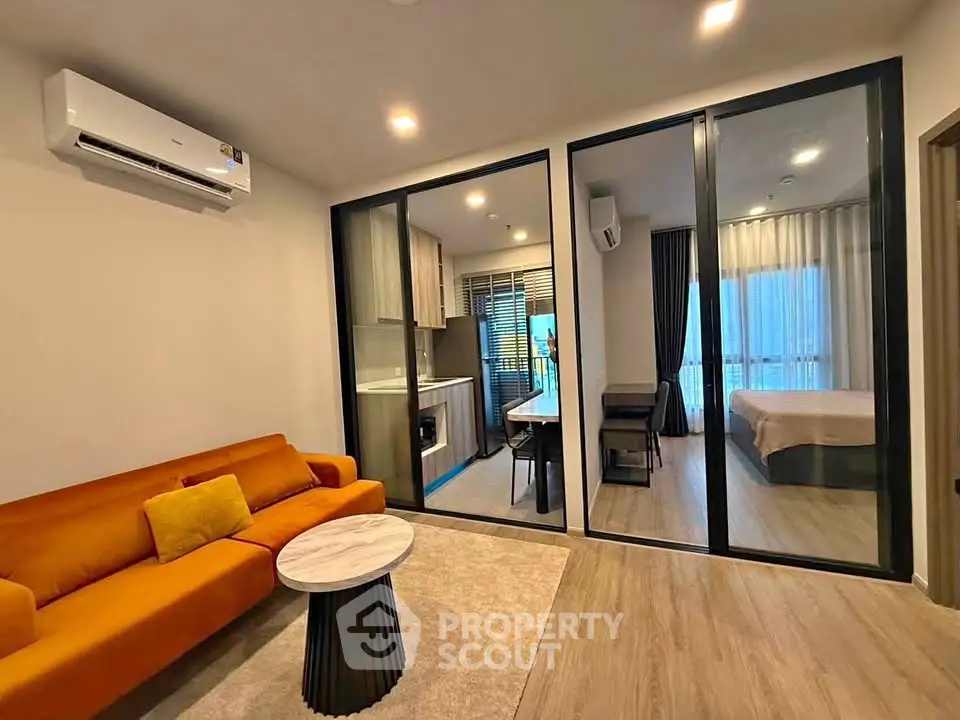 Modern apartment interior with open living room and kitchen, featuring stylish furniture and bright lighting.