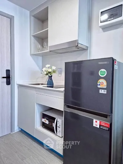 Modern compact kitchen with sleek appliances and stylish cabinetry in a contemporary apartment.