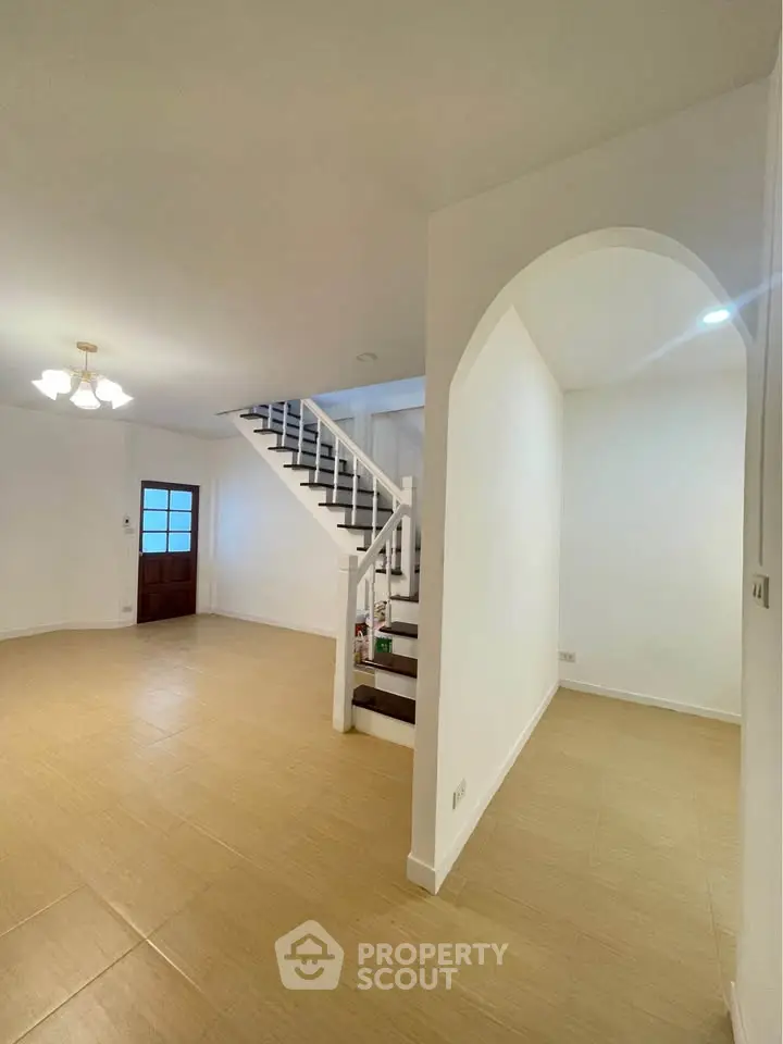 Spacious living area with elegant staircase and modern lighting, perfect for family gatherings.