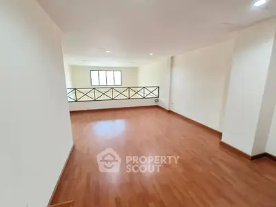 Spacious empty room with wooden flooring and large window, ideal for customization.