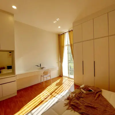 Bright bedroom with large wardrobe and study desk, featuring natural light and modern design.